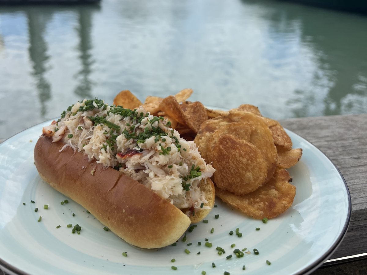 A crab roll and kettle chips on the deck at Woodward's, with the harbor behind
